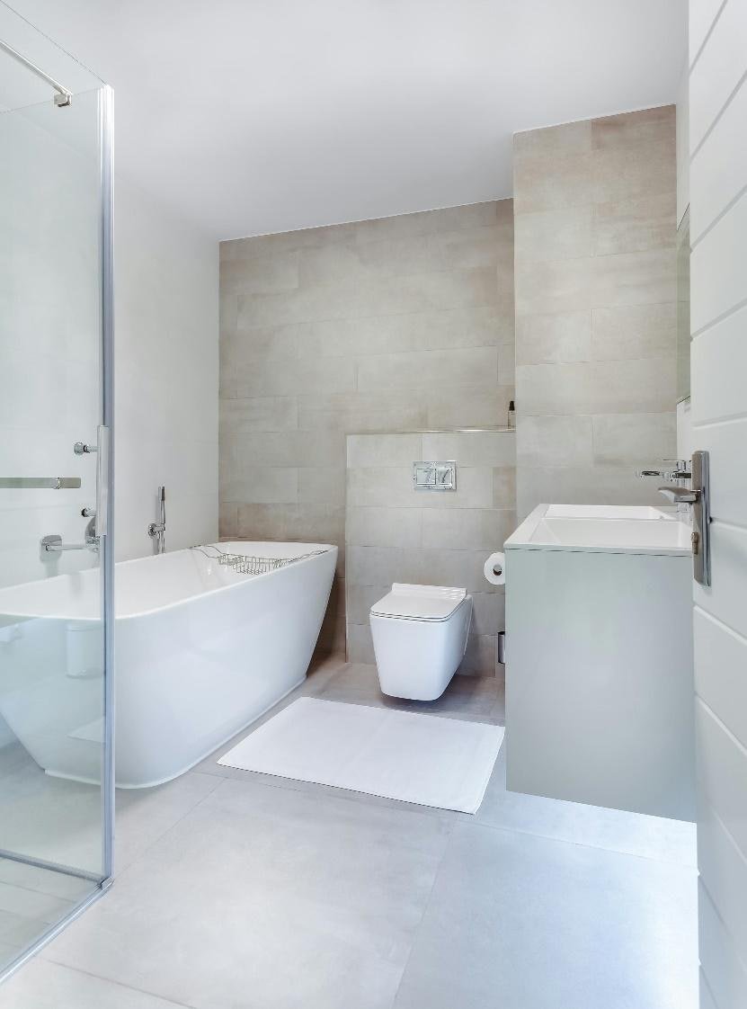 Bright bathroom with a freestanding bathtub, glass shower screen, and pale stone-look wall tiles