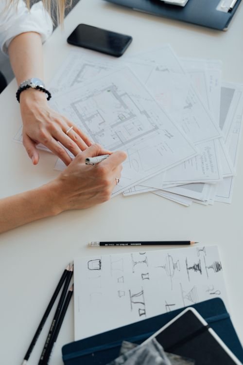 Illustrative hands reviewing a floor plan with drawing tools