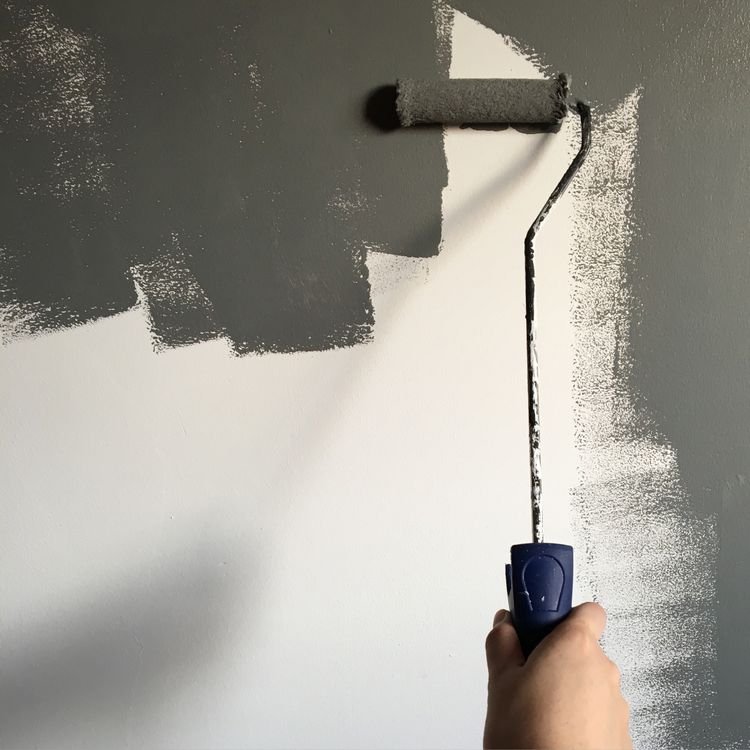 Illustrative hand applying paint to an interior wall with a roller