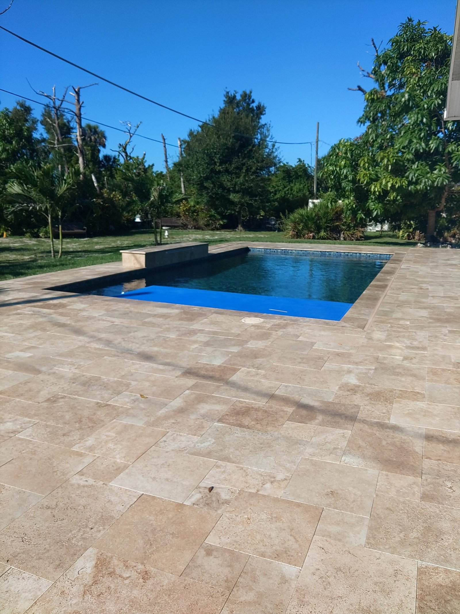 Warm beige travertine in an ashlar pattern surrounding a rectangular swimming pool